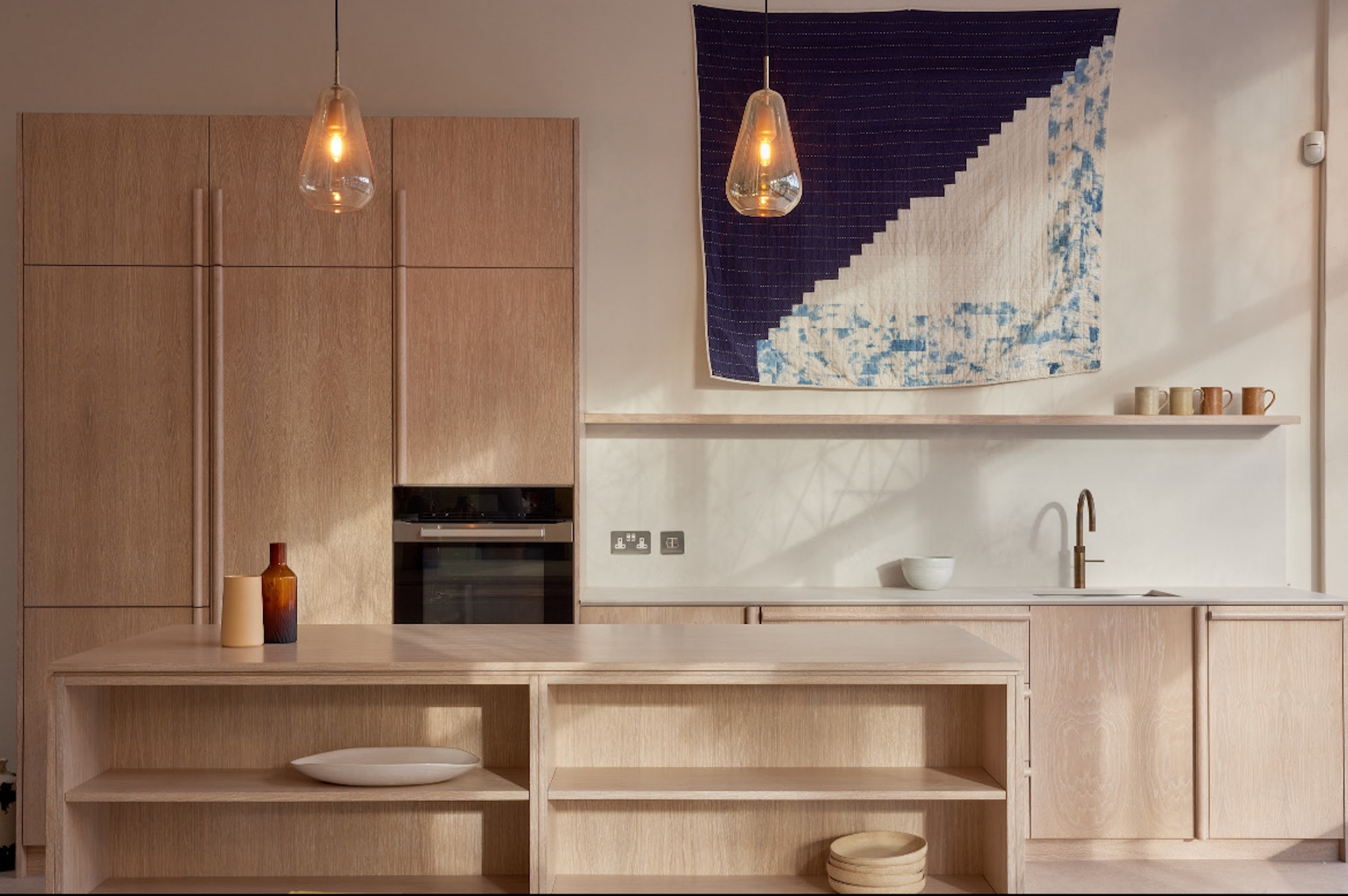 A minimalist kitchen with light wood cabinetry and open shelving